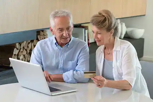 old couple managing money together on laptop
